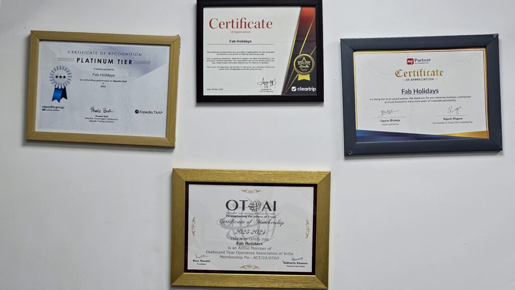 Wall display of certificates and awards earned by Fab Holidays from Expedia, Cleartrip, MakeMyTrip, and OTOAI, showcasing credibility and trust
