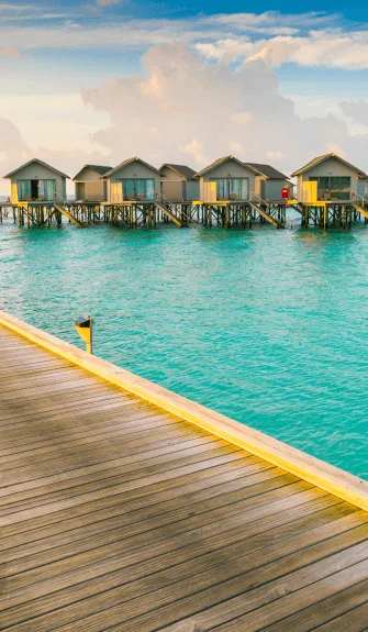 Luxury overwater villas above clear turquoise sea – Fab Holidays, the best travel agency in Delhi.