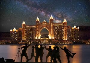 Group of tourists celebrating in front of Atlantis The Palm at night, included in a Dubai city tour package by Fab Holidays