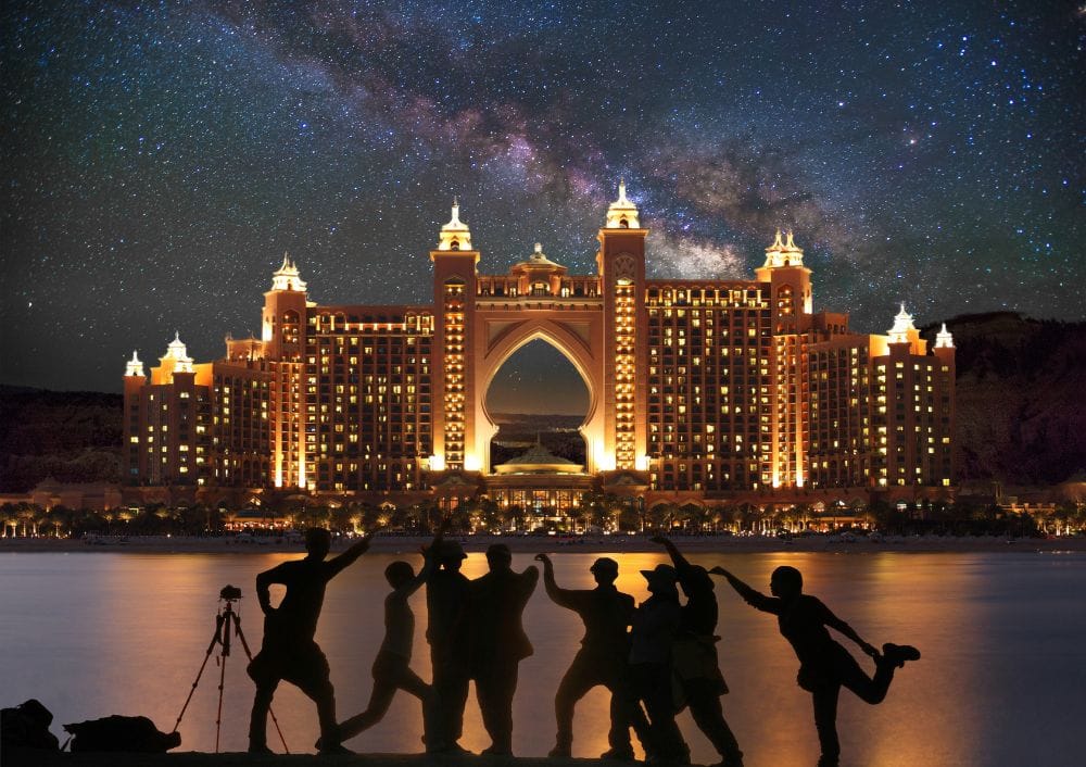 Group of tourists celebrating in front of Atlantis The Palm at night, included in a Dubai city tour package by Fab Holidays