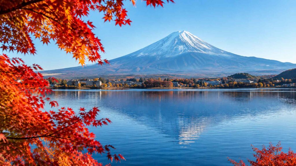 Snow-capped Mount Fuji reflected in Lake Kawaguchiko framed by red maples, a scenic stop for Japan autumn foliage 2026 — Fab Holidays, Best Travel Agency in Delhi